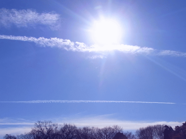 太陽の下、横(―)に進んでいく飛行機雲