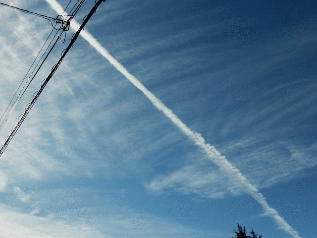 白雲の沙幕(しゃまく)と交差する飛行機雲