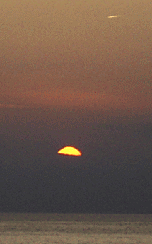 沈む夕陽と海　飛行機雲